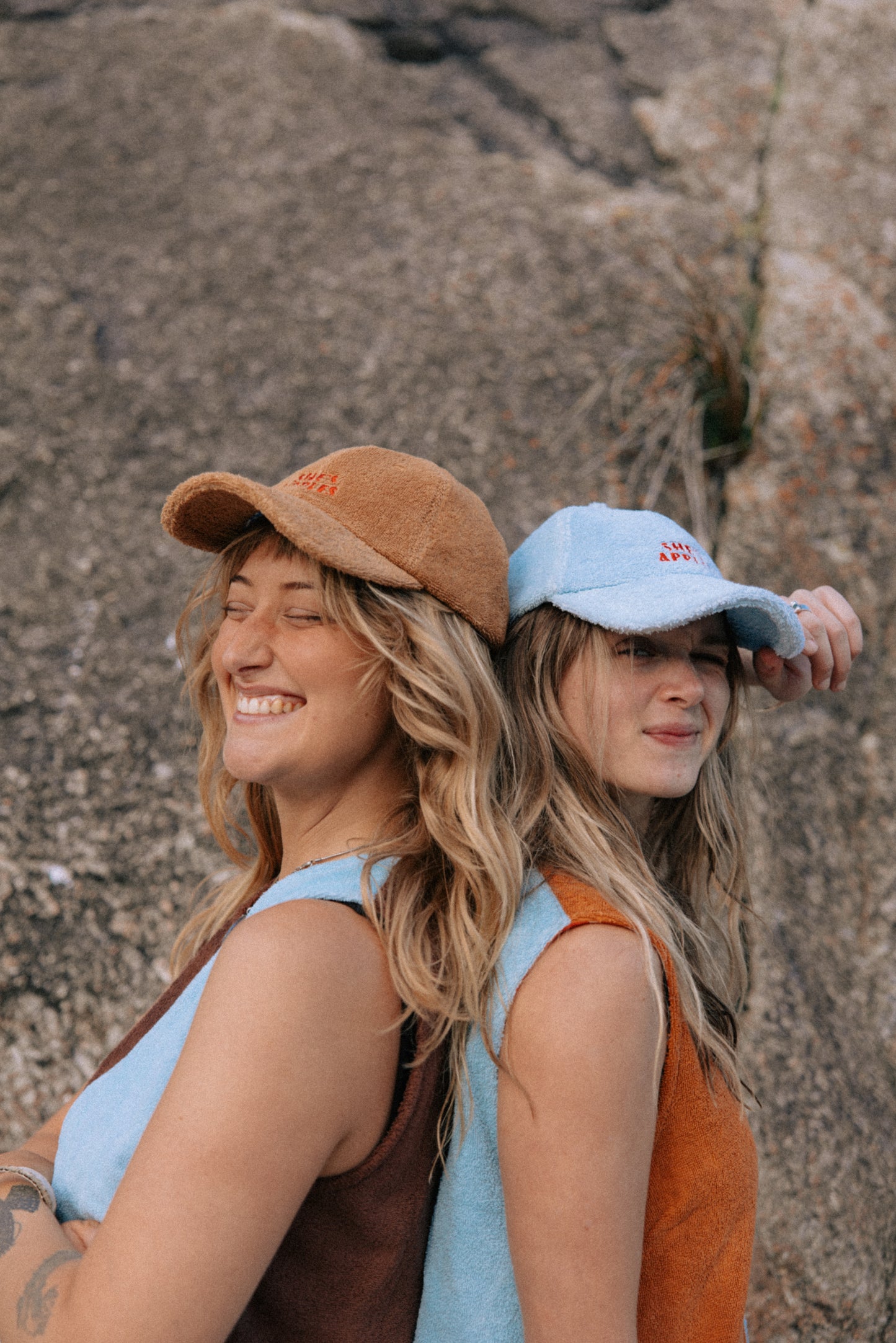 Two women wearing hats against a rocky background