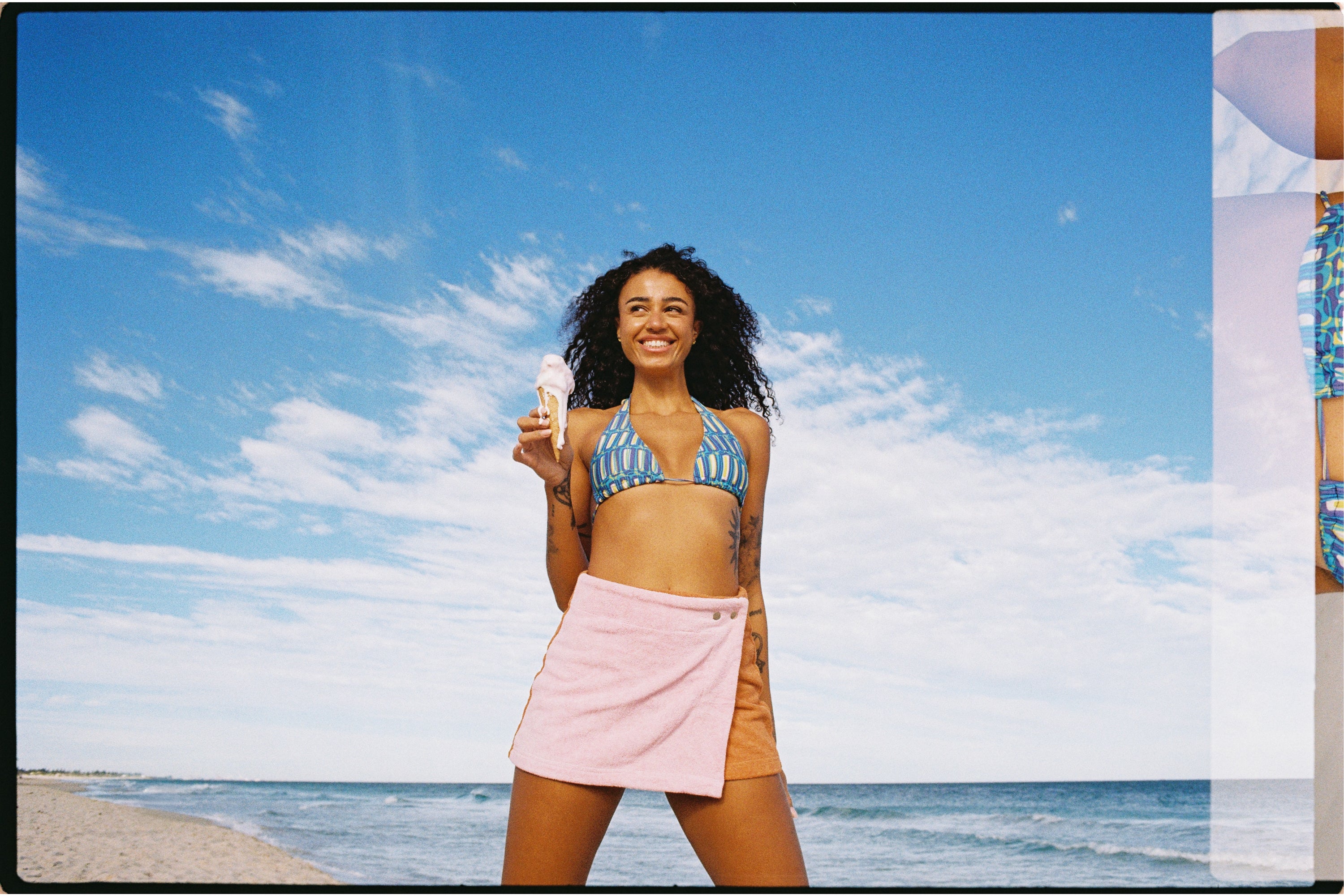 Woman wearing Wattle Wrap skirt on the beach with iceacream. Smiling